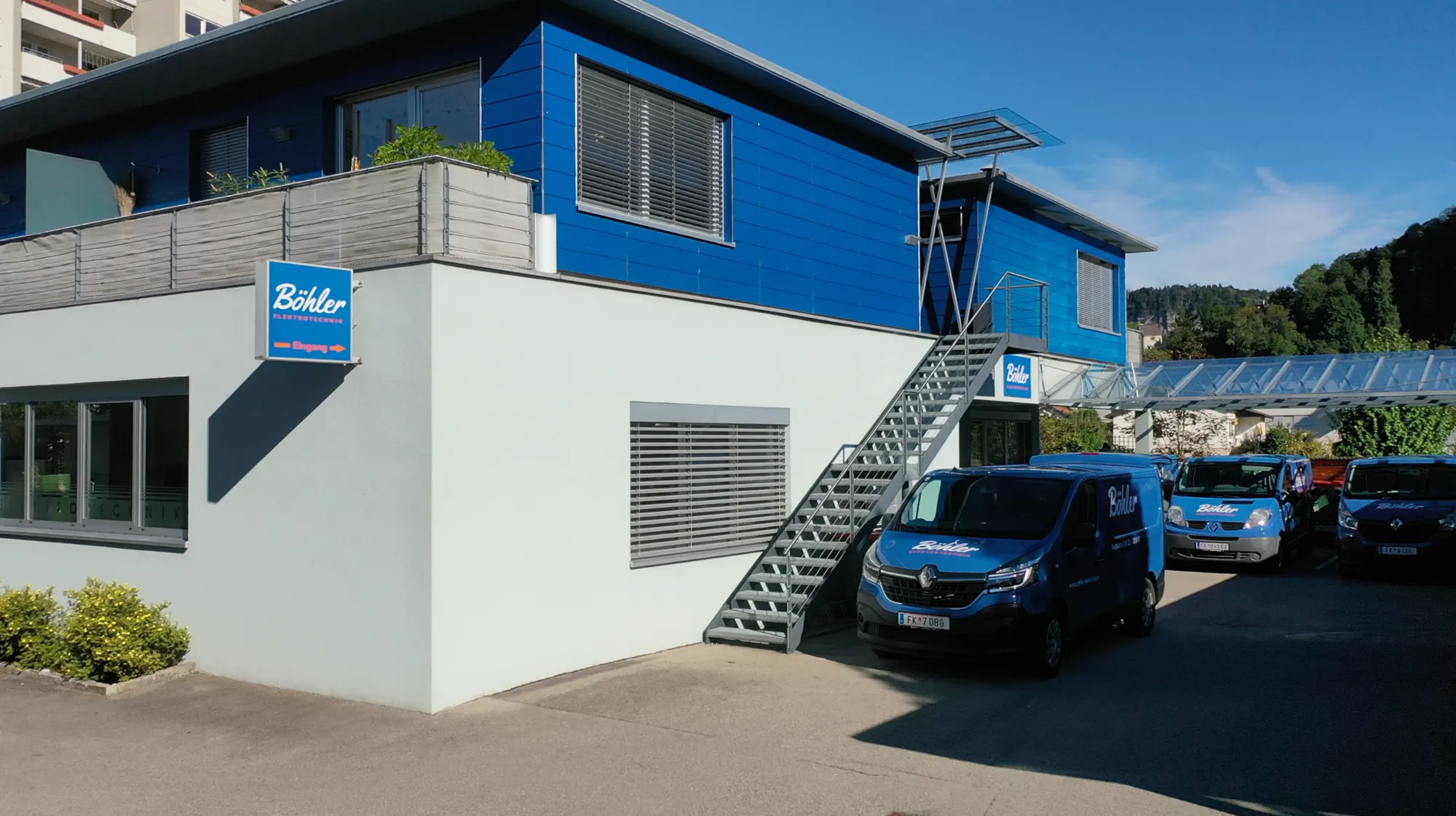 Das blau-weiße Betriebsgebäude von Böhler Elektrotechnik mit Firmenbussen